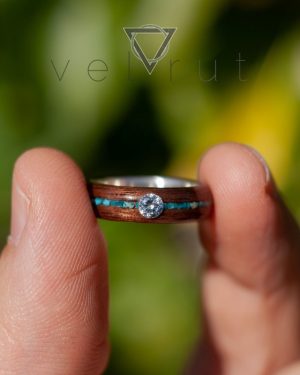 Nişan veya evlenme teklifi için tercih edilen, gümüş astar ve ortalı ince koyu firuze/turkuaz dizili ve tektaşlı ceviz sarma ahşap yüzük.